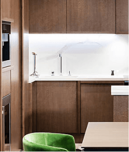 Modern luxury kitchen with dark wood cabinetry and a green velvet chair