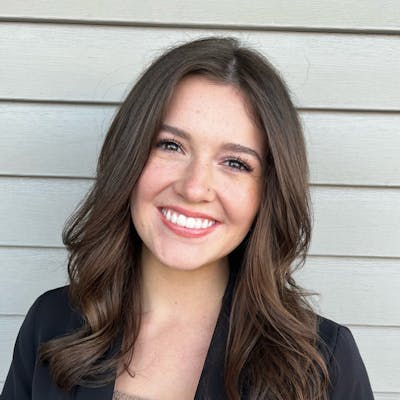 Portrait of a smiling woman with long brown hair in a black blazer