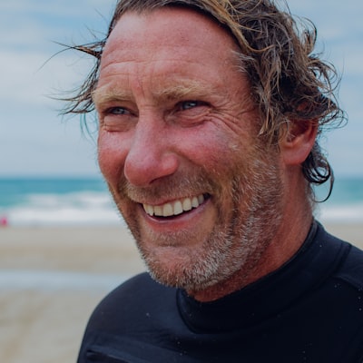 Portrait of a smiling older man in a wetsuit at the beach