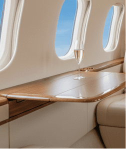 Private jet cabin interior with a glass of champagne on a wood table